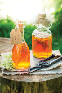 yellow liquid and herbs in tapered glass jars sealed with corks
